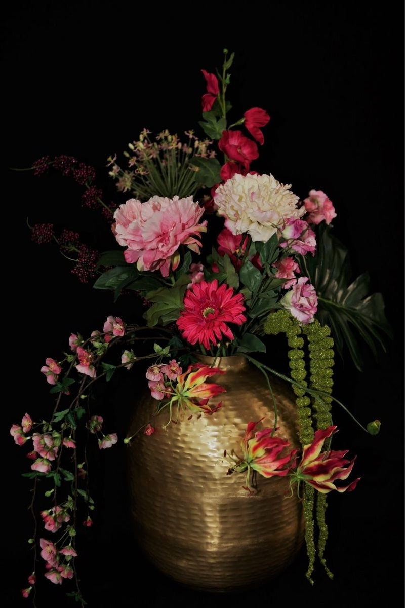 goudkleurige ronde vaas gevuld met bloemen zwarte achtergrond