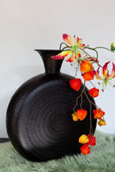 Zwarte vaas rond met motief en smalle hals met bloemen