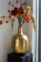 Grote gouden vaas rond met hals gevuld met bloemen